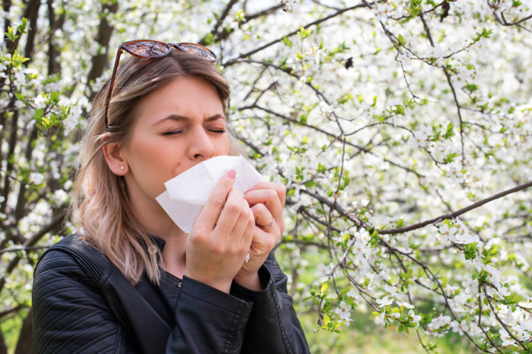 Woman sneezing into a tissue seasonal allergies