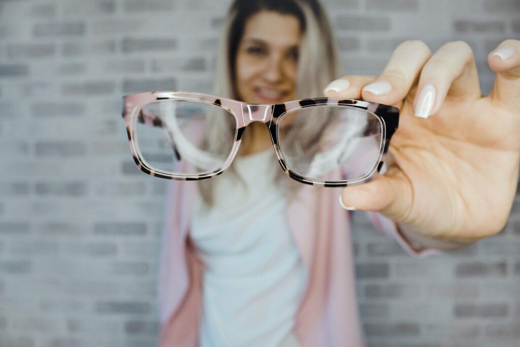 Woman holding pink and and black eyeglass frames